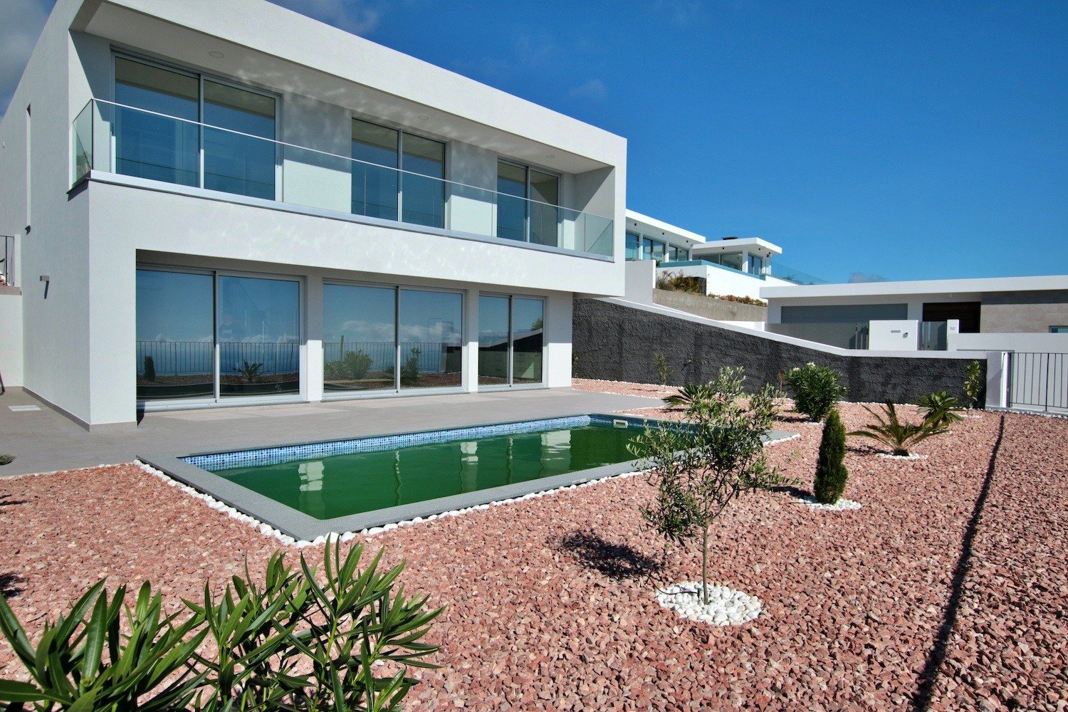 Front facade of the house with a garden and swimming pool