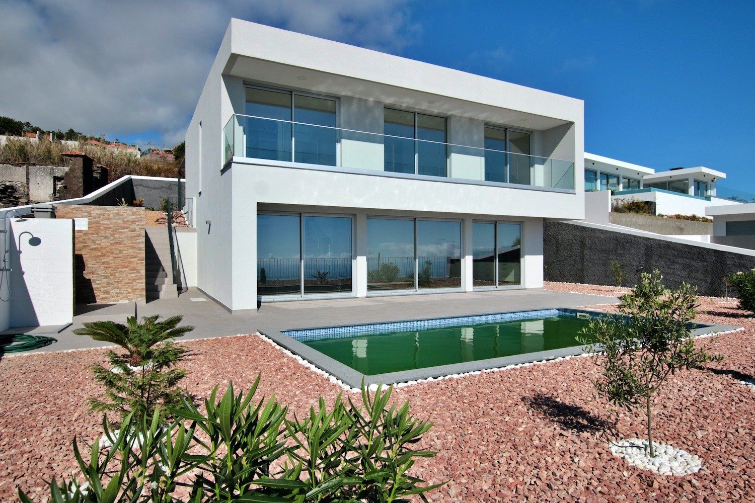 Front facade of the house with a garden and a swimming pool