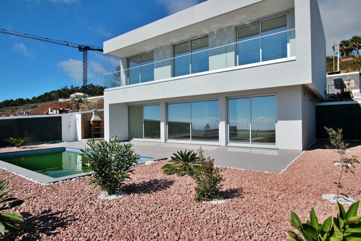 Front facade of the house with a garden and a swimming pool