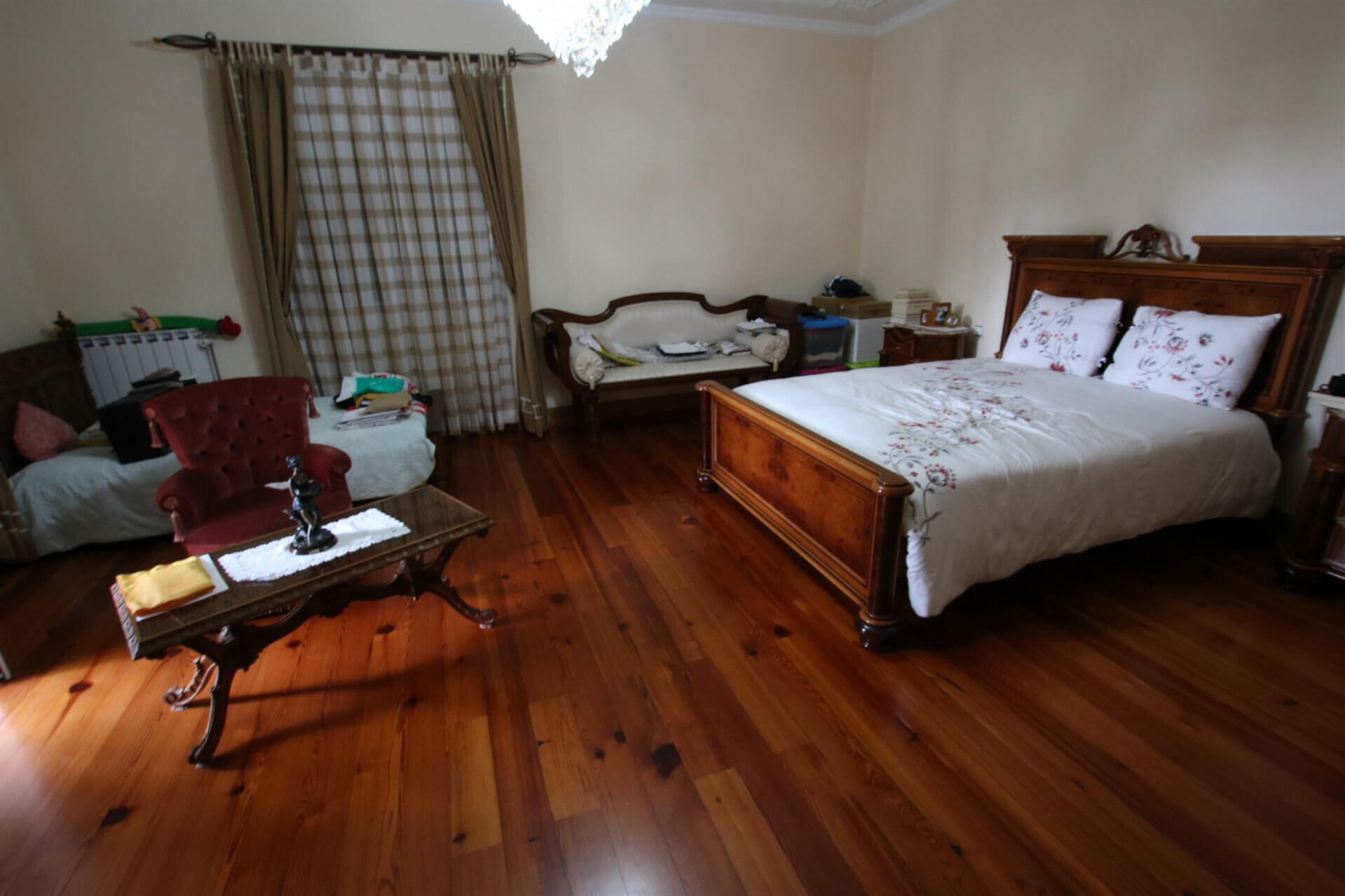 Bedroom with wooden floor, 2 beds, a sofa, a table and a chair