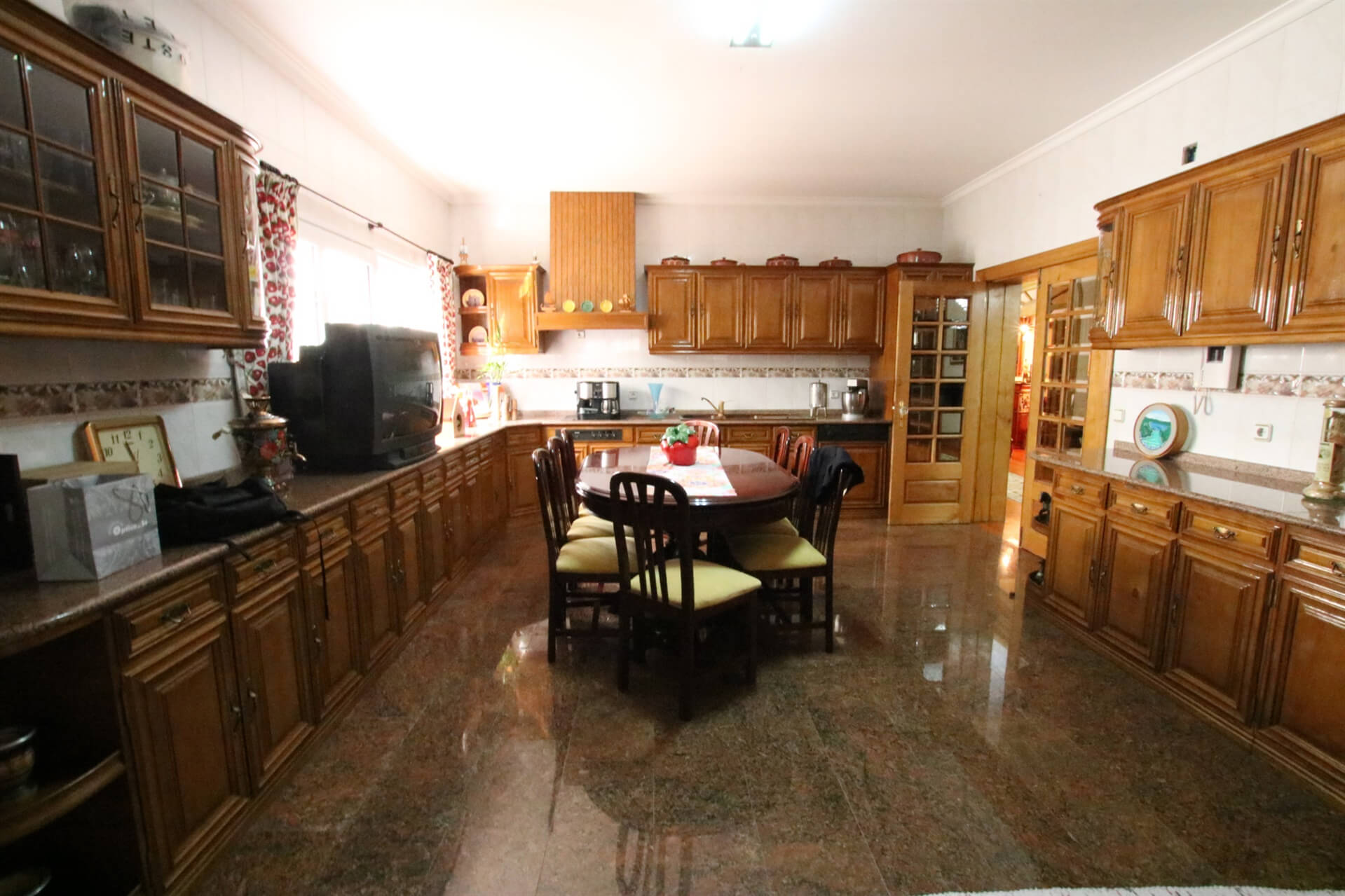 A large kitchen with wooden cupboards and a table in the middle of it with chairs around the table