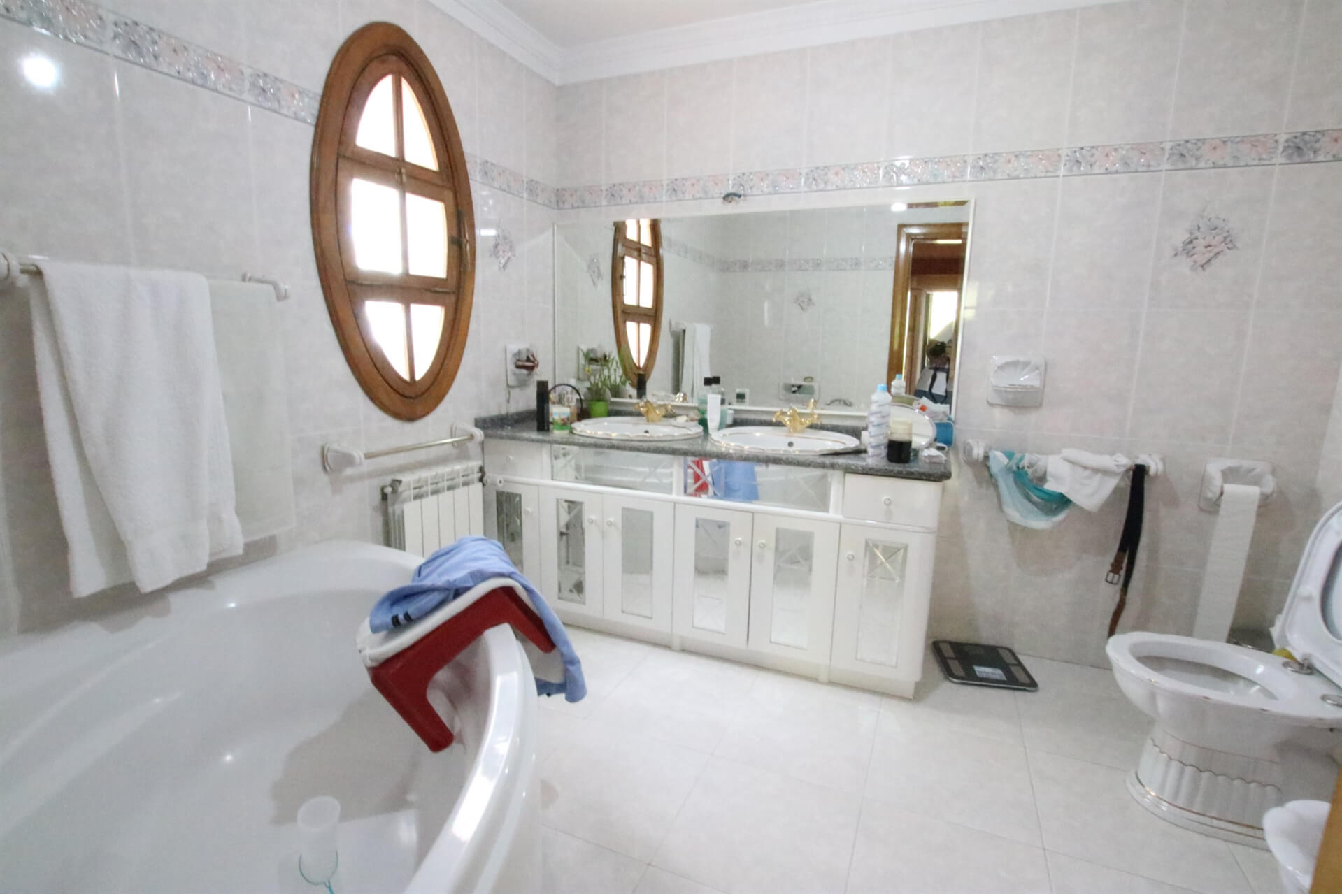 Bathroom with big a bath tub, a toilet seat, a window and a basin